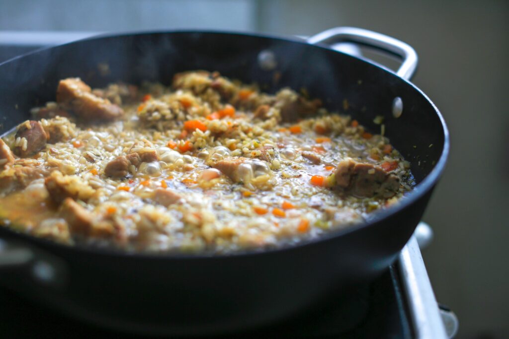 Closeup of a bubbling paella with vegetables and meat in a skillet, capturing the essence of home-cooked meals.